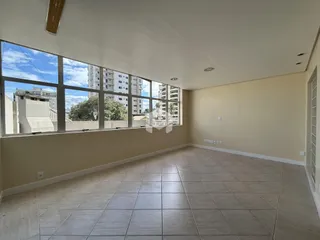 Sala ampla com grandes janelas que oferecem uma vista da paisagem urbana.