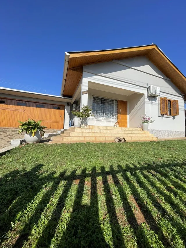 Fachada de uma casa em Lajeado, Brasil com jardim gramado e degraus de pedra.