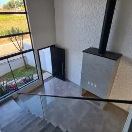 Vista de um ambiente interno com piso claro e grade de vidro.