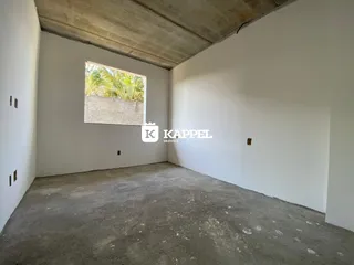 Foto de um cômodo vazio com piso de concreto e uma pintura na parede.
