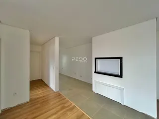Hall de entrada com piso de madeira clara e paredes brancas.
