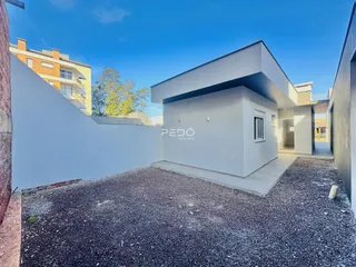 Fachada moderna de uma residência em Lajeado, Brasil, com muro branco e área de terra.