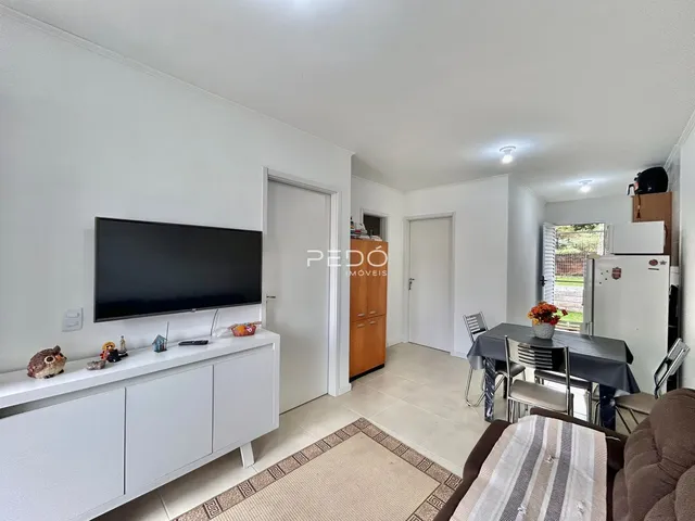 Sala de estar com televisão e área de jantar em um imóvel.