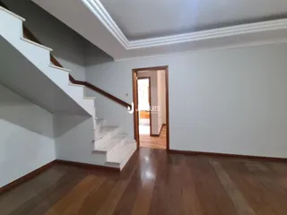 Vista de um corredor com escadaria e piso de madeira.