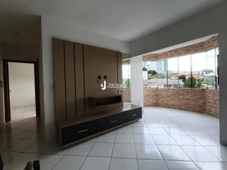A sala de estar apresenta piso de cerâmica branca e paredes em tom neutro.