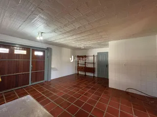 Ambiente interno com piso de tijolo vermelho e paredes brancas.