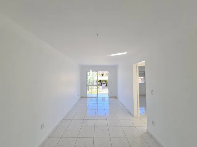 A foto mostra um corredor interno claro com piso de cerâmica.