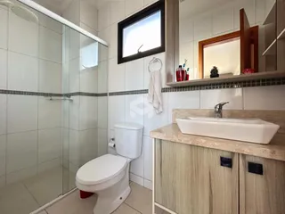 Foto de um banheiro com box de vidro e louças brancas.