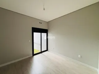 Vista interna de um cômodo com piso de madeira clara e parede lisa.