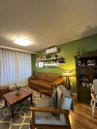 Esta é uma foto de uma sala de estar com sofá marrom e piso de madeira.