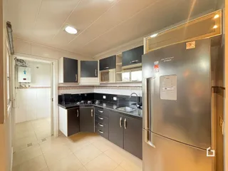 Foto interna de uma cozinha com armários escuros e bancada escura.