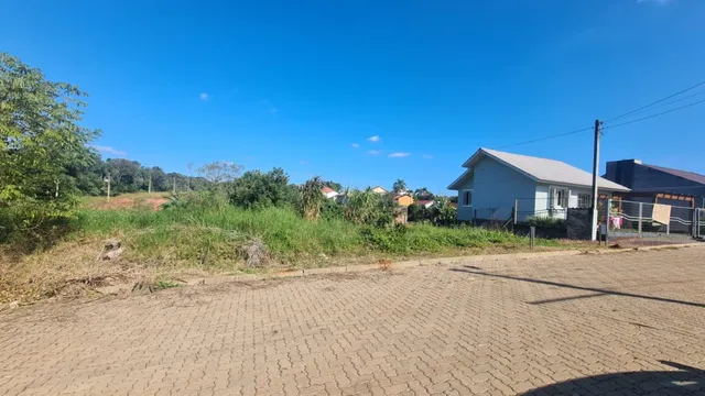 Vista externa de uma propriedade com terreno seco e vegetação rasteira.