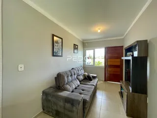 Sala de estar com sofá cinza e piso de madeira clara.
