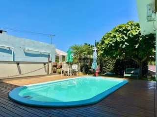 Piscina ao ar livre com deck de madeira e jardim.