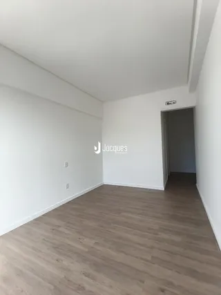 Corredor interno de um imóvel com piso de madeira clara.