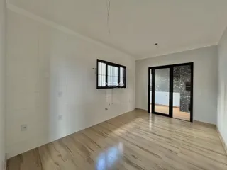 Ambiente interno com piso de madeira clara e paredes brancas.