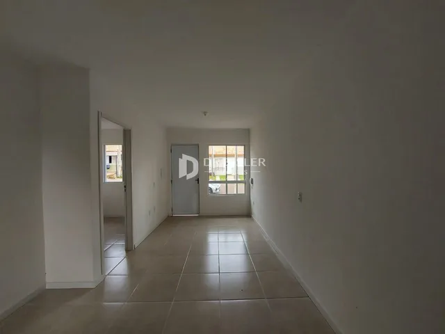 Hall de entrada de uma residência com piso de cerâmica clara.