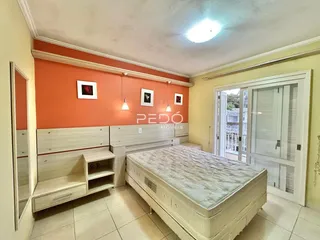 Quarto com cama e armários de madeira na parede laranja.