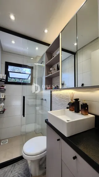 Foto interna de um banheiro moderno com revestimento branco e piso claro.