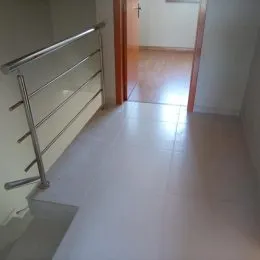Hall de corredor com piso claro e grade metálica.