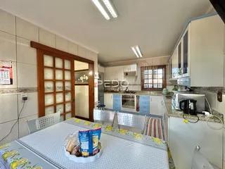 Foto interna de uma cozinha com armários brancos e portas de madeira em Lajeado.