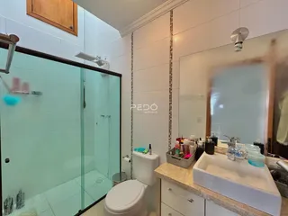 Foto de um banheiro com box de vidro e pia em um imóvel no Brasil.