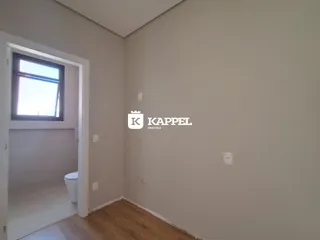 Foto de um cômodo interno com piso de madeira e uma porta de acesso a um banheiro.