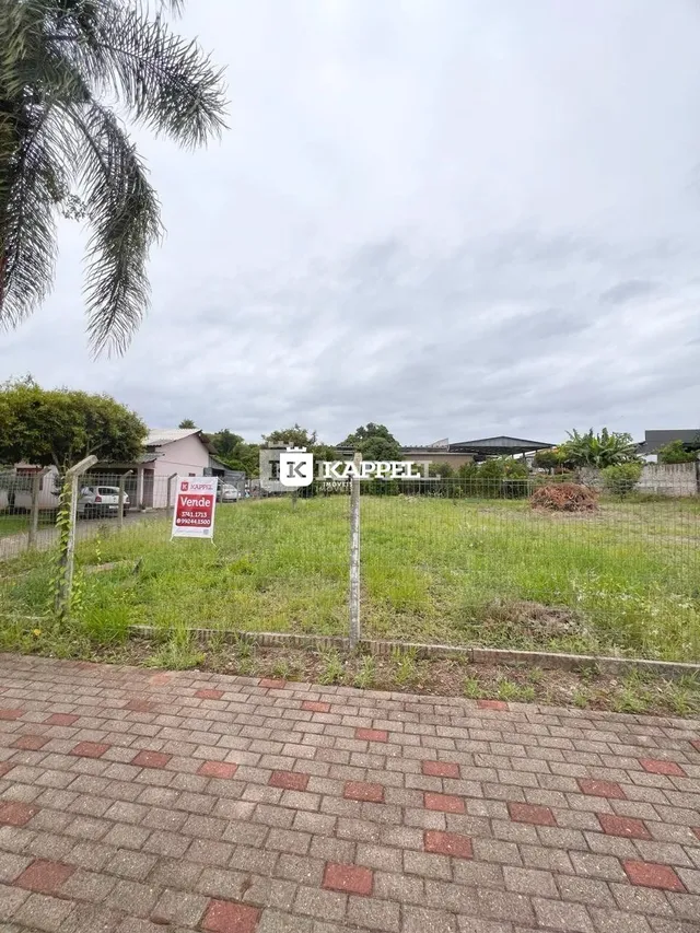 Vista externa da propriedade mostrando gramado e cerca no primeiro plano.