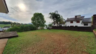 Vista externa de uma propriedade com gramado e árvores ao fundo.