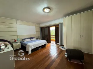 Quarto com piso de madeira e armários em um apartamento em Lajeado.