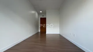 Corredor interno com piso de madeira e paredes brancas.