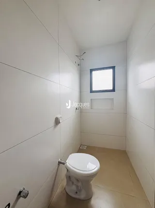 Foto de um banheiro interno com paredes brancas e piso de cerâmica.