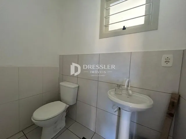 Foto de um banheiro com azulejos brancos e louças sanitárias.