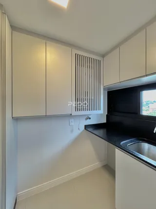 Foto de uma cozinha moderna com armários brancos e bancada escura.