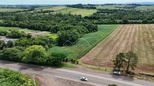 Vista aérea de paisagem rural com campos cultivados e vegetação densa.