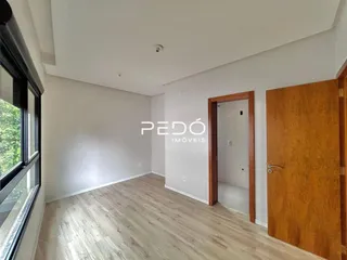 Sala de estar com piso de madeira clara e parede branca.