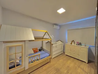 Quarto com cama de beliche de madeira e armário branco em um imóvel no Brasil.