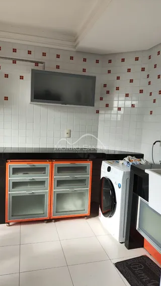 Cozinha com revestimento de azulejos brancos e eletrodomésticos visíveis.