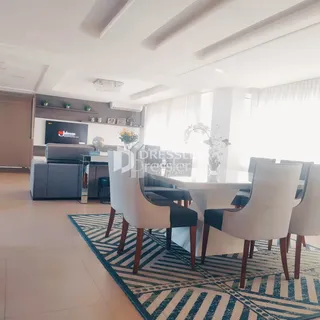 Sala de jantar iluminada com mesa e cadeiras em um imóvel no Brasil.