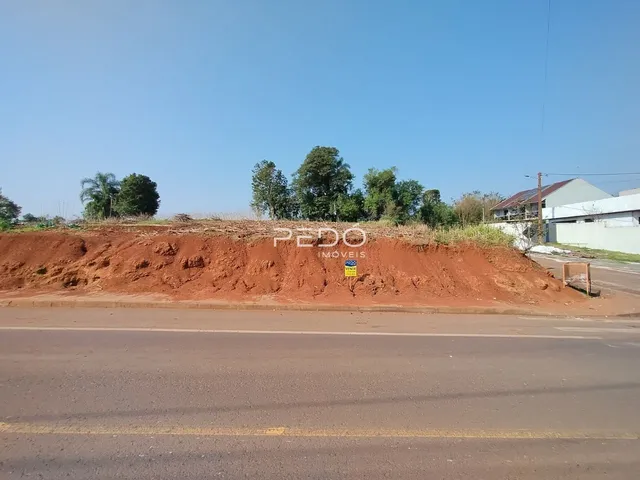 Vista da terra com solo avermelhado ao lado de uma estrada.