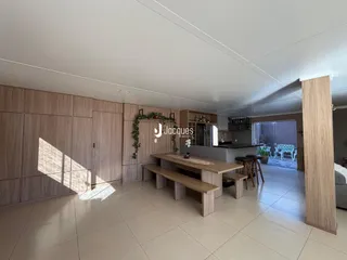 A sala de estar apresenta um ambiente moderno com piso de cerâmica e painéis de madeira.