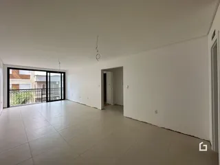Interior de uma sala ampla com piso de cerâmica e porta de vidro para a varanda.
