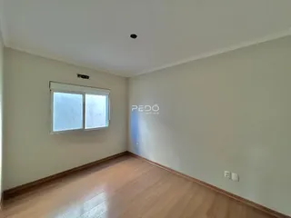 Ambiente interno de uma sala com piso de madeira e janela.