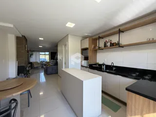 Ambiente interno de uma sala de estar com cozinha integrada e piso de porcelanato claro.