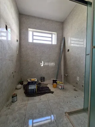 Foto de um cômodo interno com paredes brancas e piso de concreto.