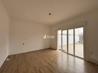 Ambiente interno com piso de madeira clara e porta de vidro para área externa.