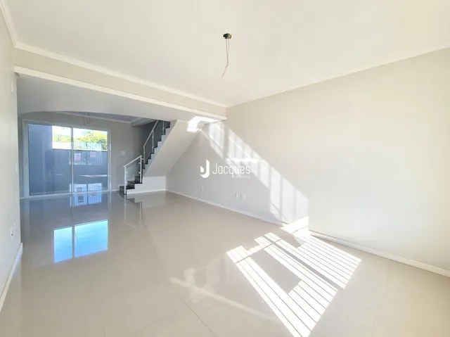 Ambiente interno de uma sala ampla com piso claro e luz natural.