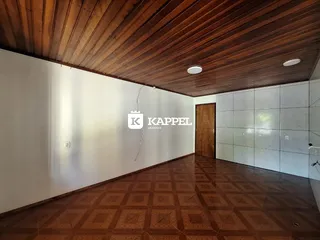 Ambiente interno com piso de ladrilhos e forro de madeira em uma sala ampla.