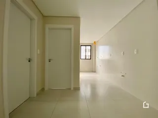 Corredor interno de uma residência com paredes brancas e piso claro.