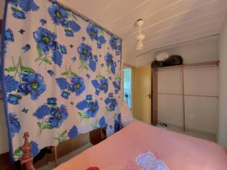 Foto de um quarto com cama rosa e papel de parede floral azul e branco.